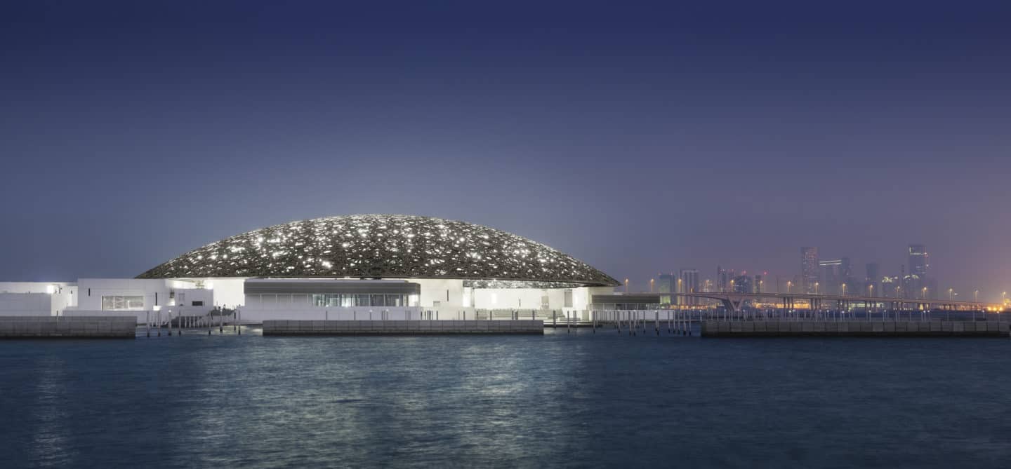 Louvre Abu Dhabi’s exterior with Abu Dhabi’s skyline at night